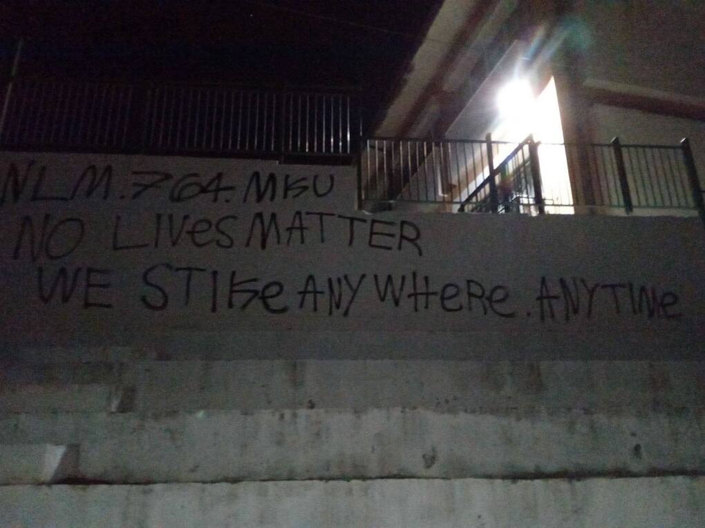 Vandalism on a wall that reads "NLM. 764. MKU. No lives matter. We strike anywhere, anytime."