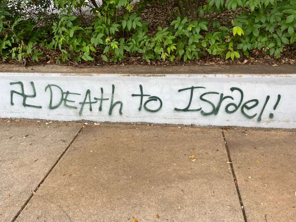 Graffiti of a swastika and the phrase "Death to Israel!" spray-painted on a retaining wall outside Congregation Beth Israel in Austin, Texas, April 24, 2026 