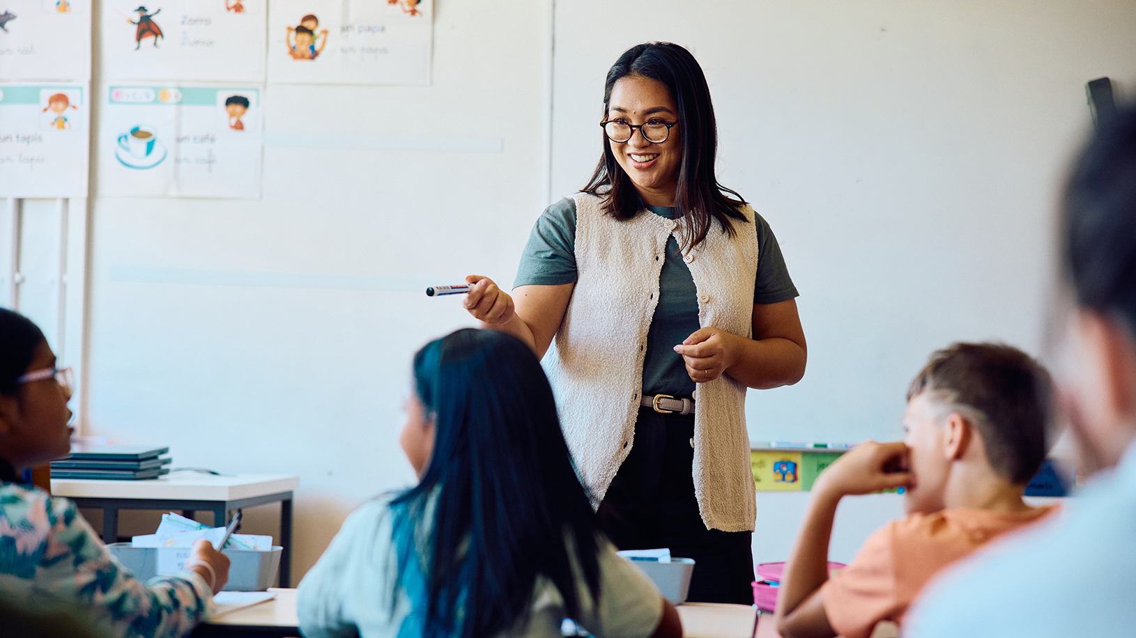 Teacher smiling while teaching from front of classroom