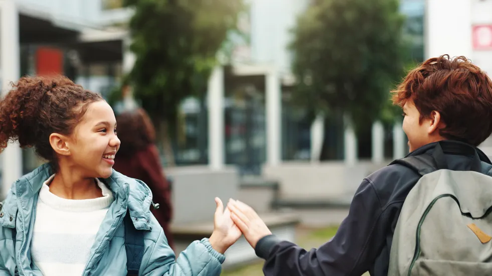 Kids walking by each other outside and giving each other a high five