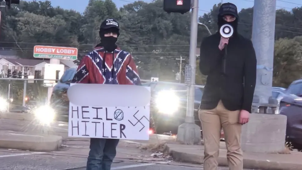 Two men stand outside a restaurant with an antisemitic sign