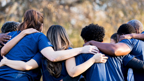 Rearview of friends linking arms in unity