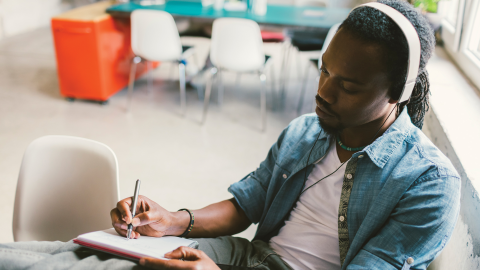 African man podcasting and taking notes