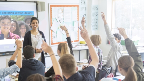 Students raising hands in a classroom to answer a question by the instructor