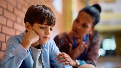 Boy being consoled by teacher