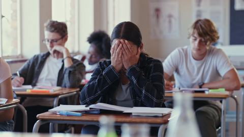 Student covering her face with her hands while sitting in class