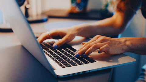 Hands Typing on Laptop Keyboard in Modern Workspace