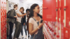 Teenage girl standing at her locker and being bullied at high school
